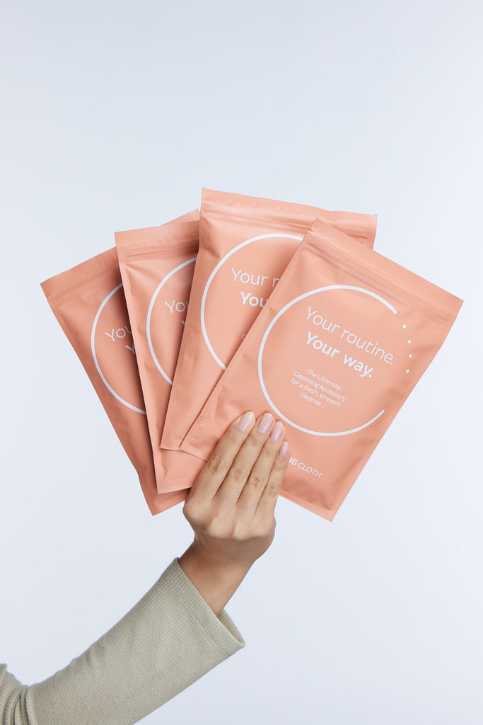 Hand holding up 4 cleansing cloth packets