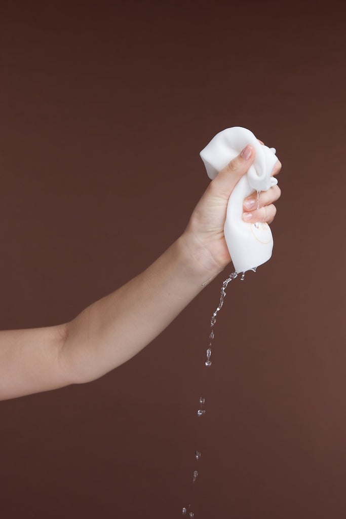 Hand squeezing water from Cleansing Cloth